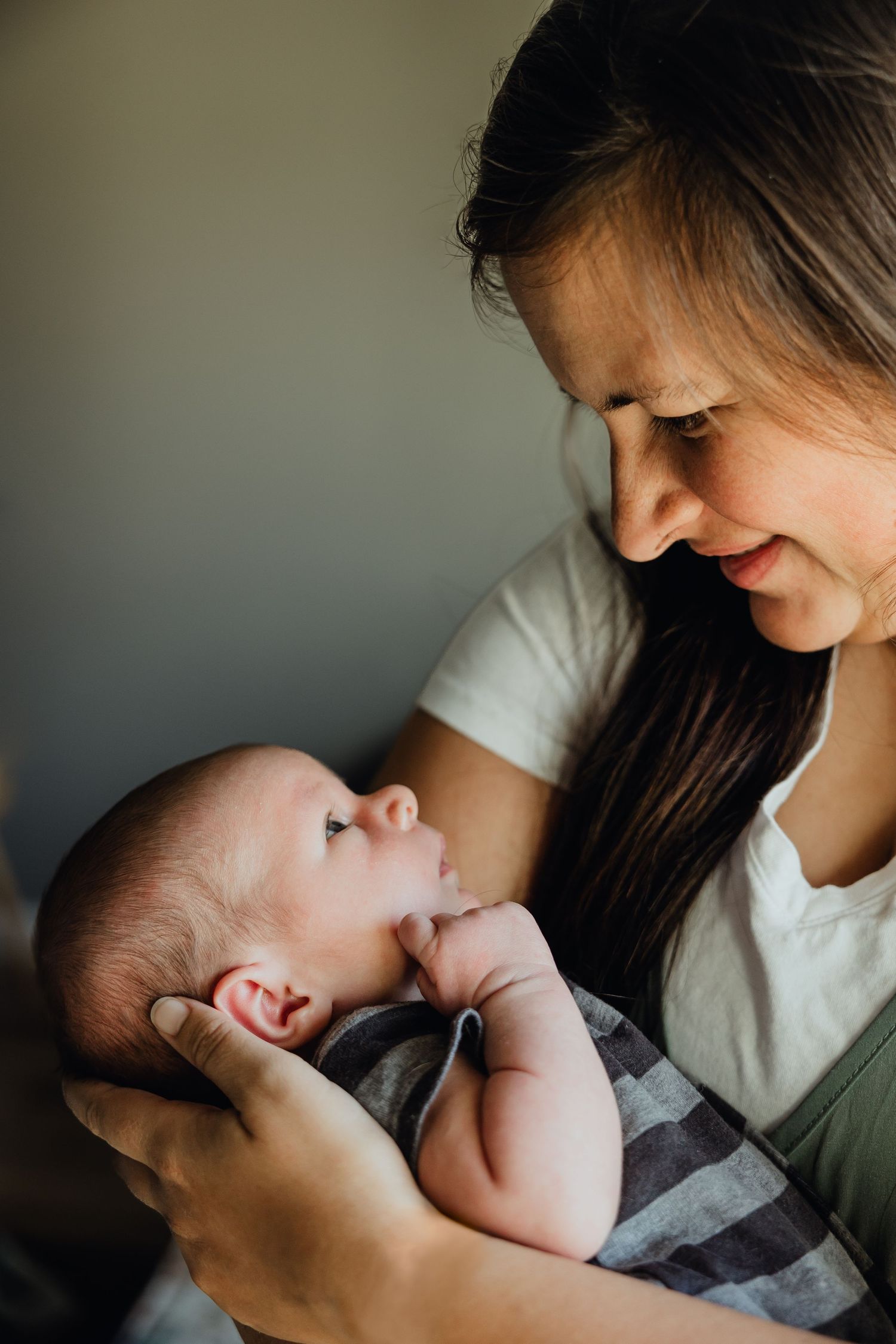 A tender moment captured as a baby and parent share an intimate bonding moment in soft natural light.