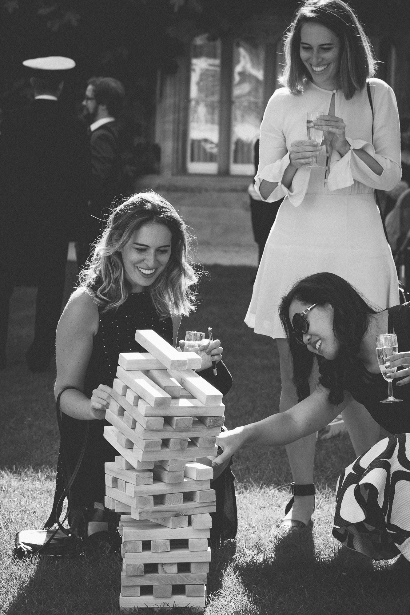 wedding reception party games with guests in sun on lawn playing giant jenga as tower falls