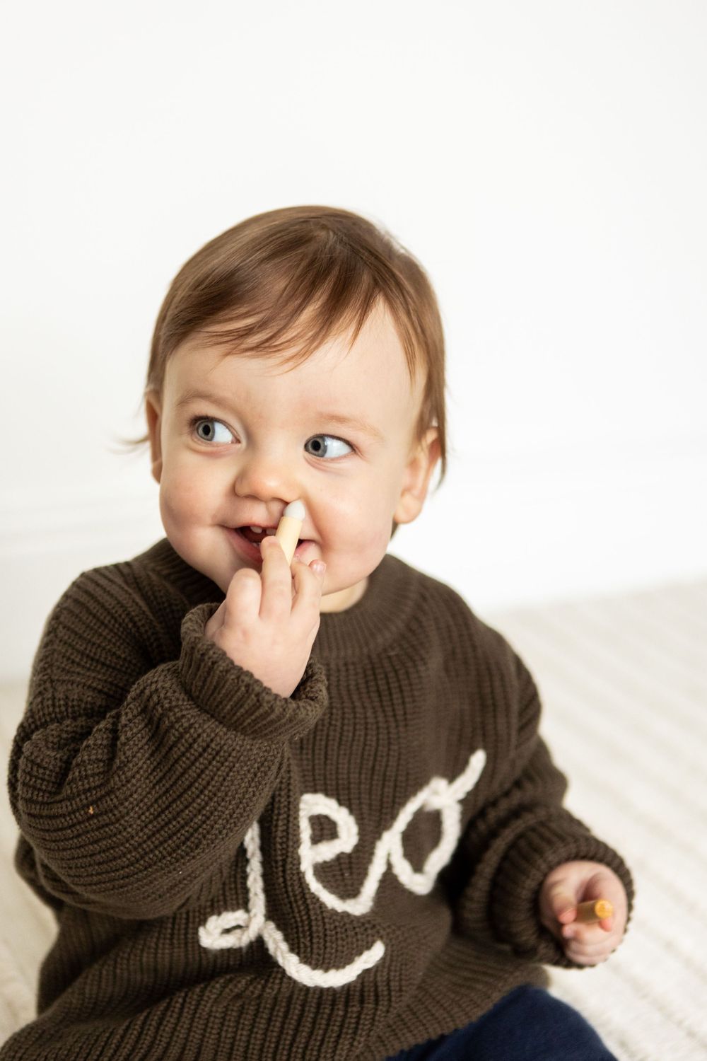 baby leo giving the side eye to his dad while eating the wooden candles