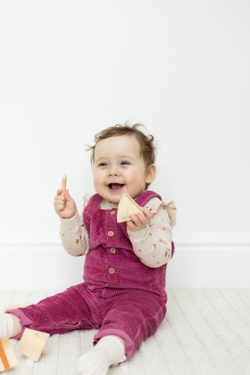 smiley little girl holding wooden cake while sitting up