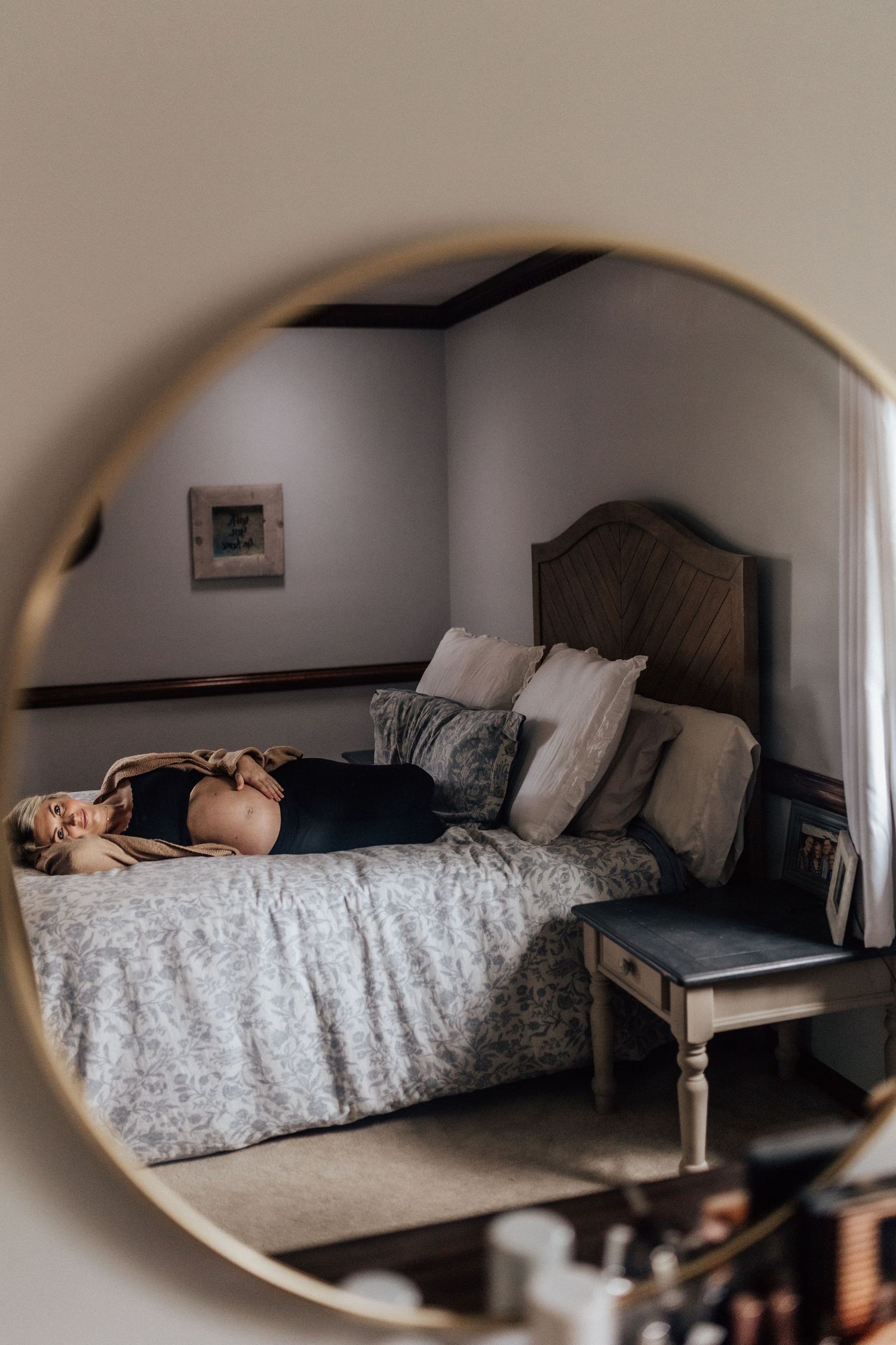 pregnant woman laying on her bed holding her belly