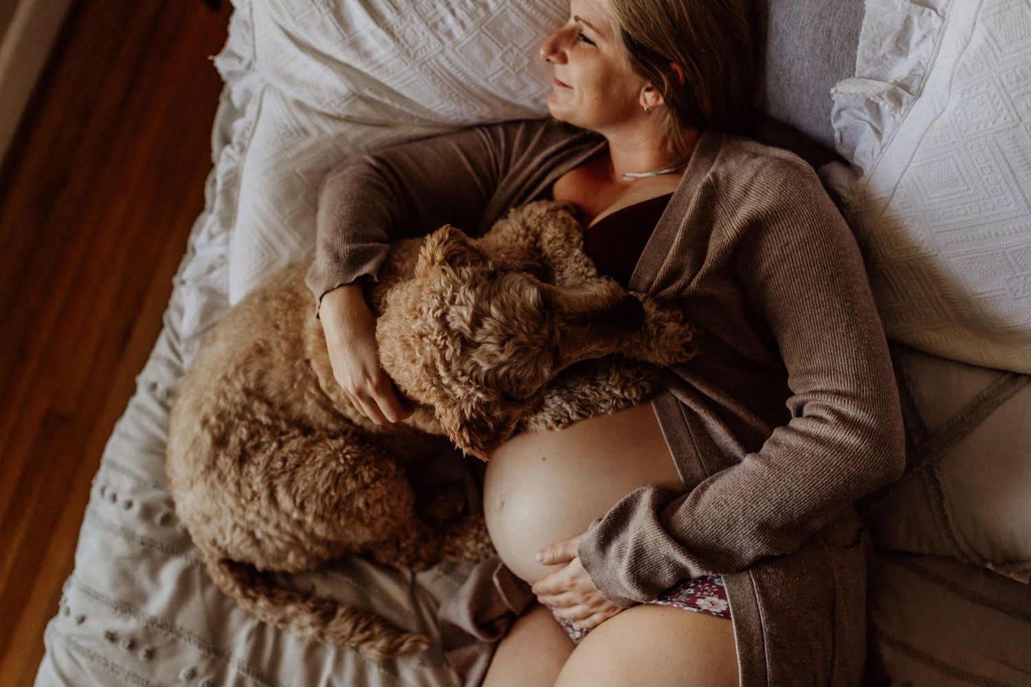 pregnant woman laying with dog on her bed in her portsmouth home