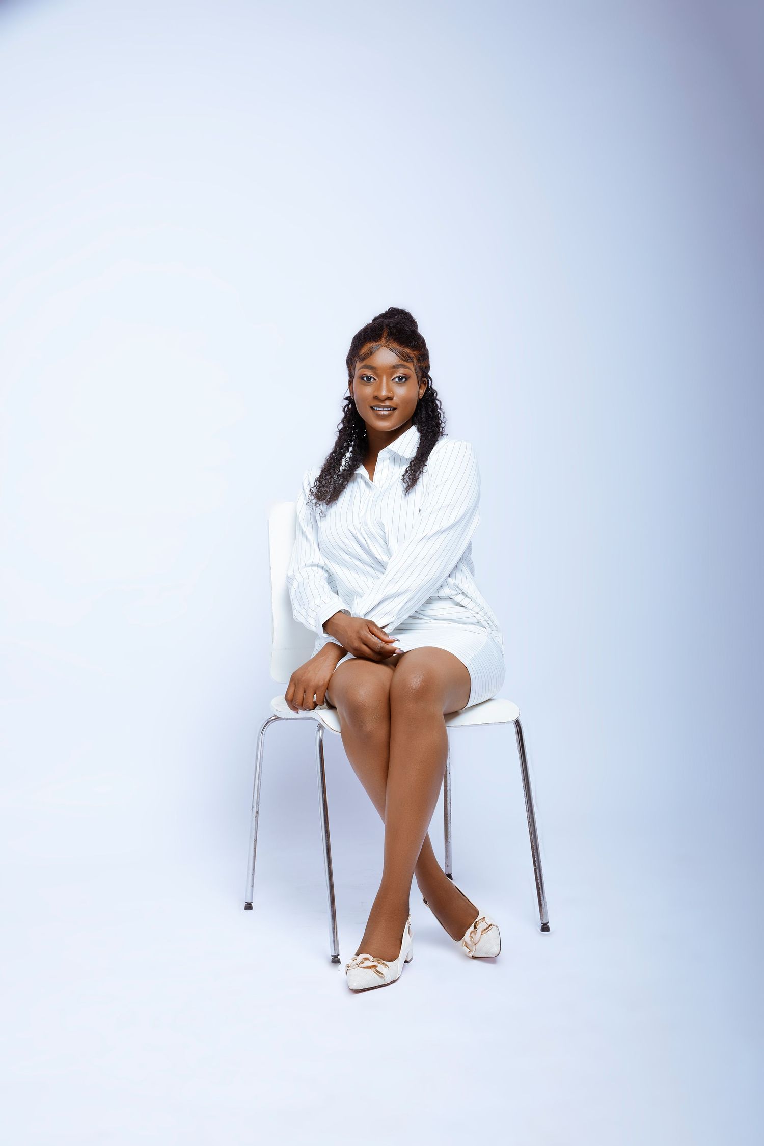 Minimalist portrait session featuring a white chair against a light gray studio background.