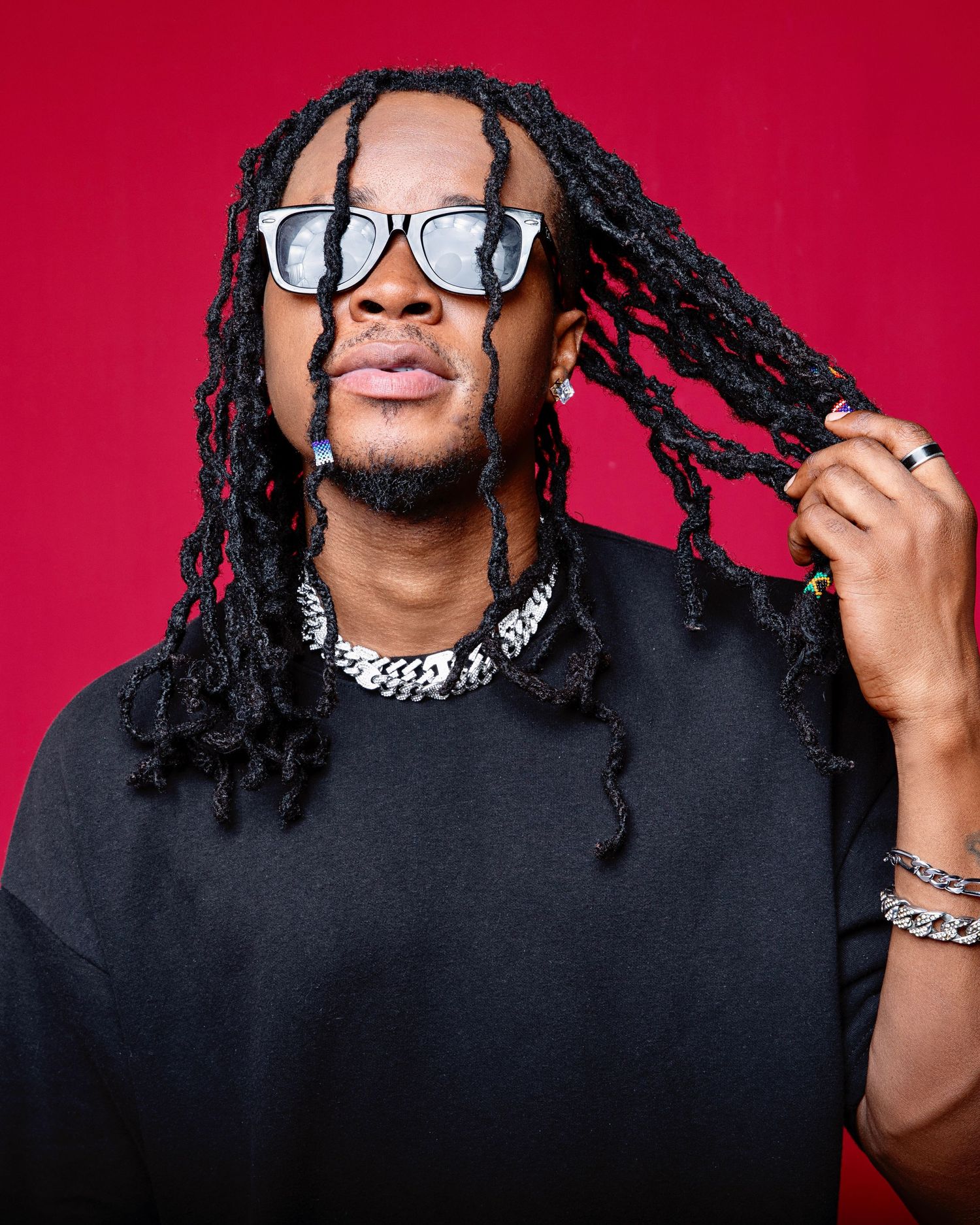 Creative portraits showing person with dreadlocks and glasses against red background.