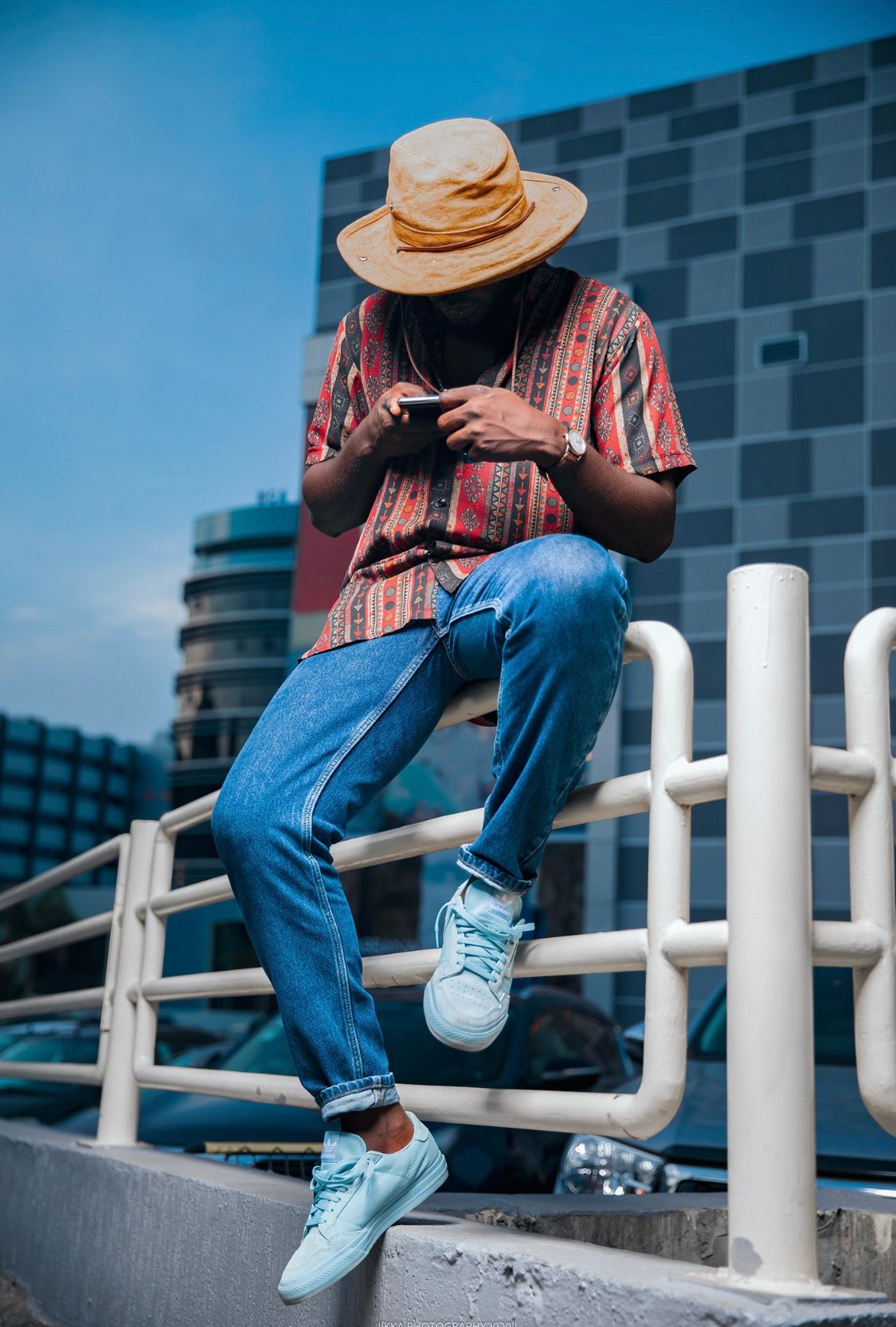 Person in casual wear and hat sitting on white railings showing different poses.