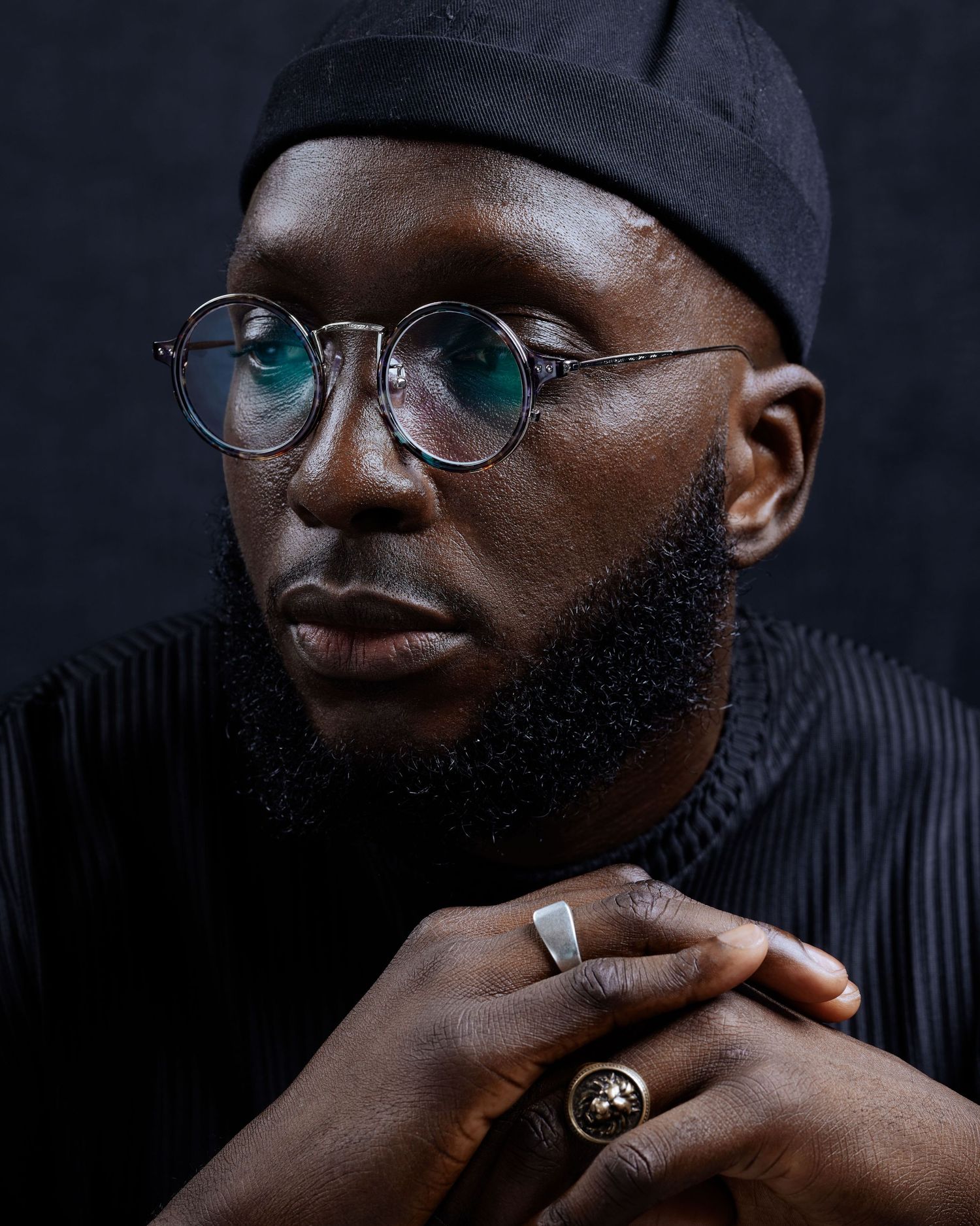 Moody portrait series showing person in black cap and glasses against dark background.