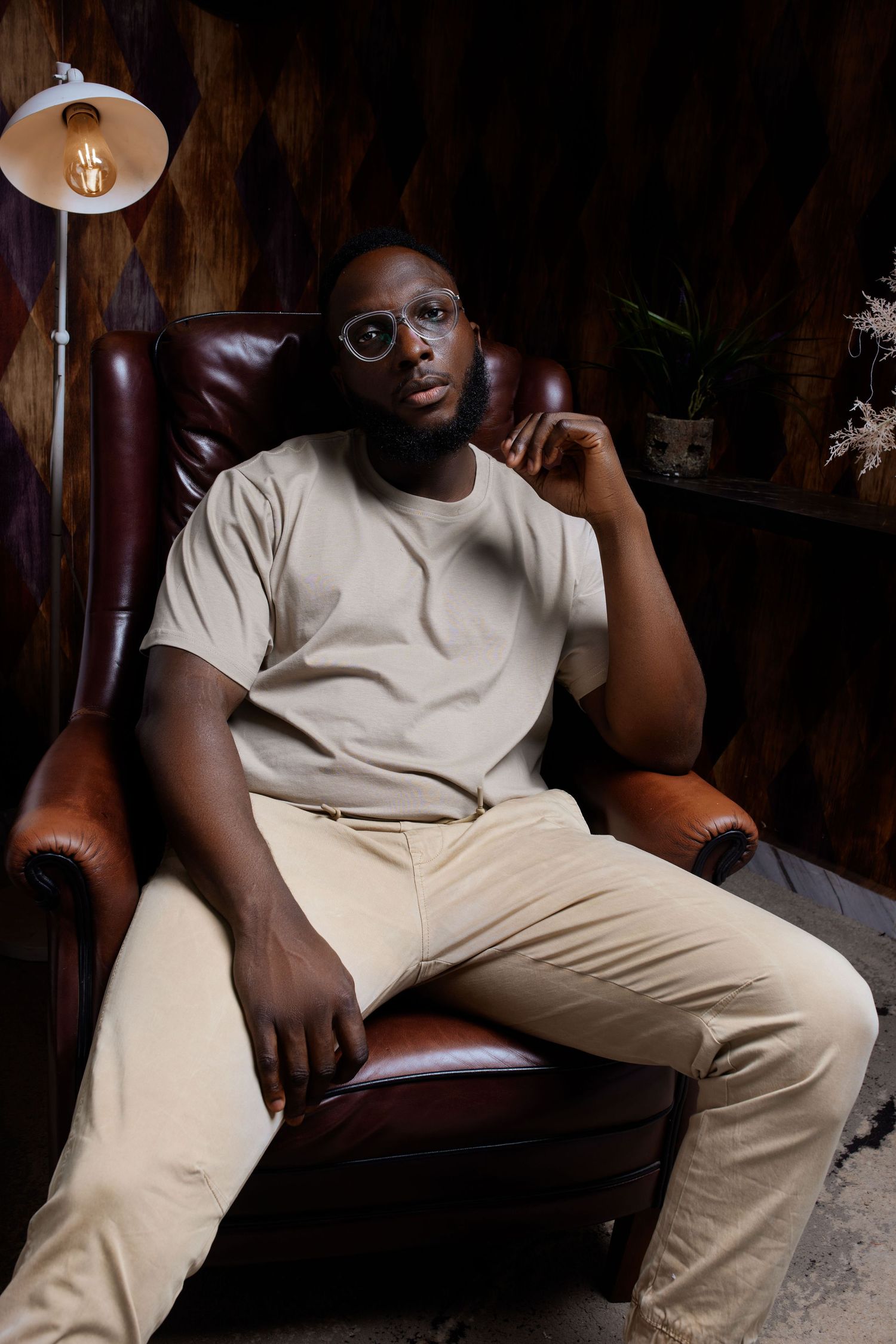 Artistic portrait series showing a person in cream colored outfit lounging on dark leather furniture.