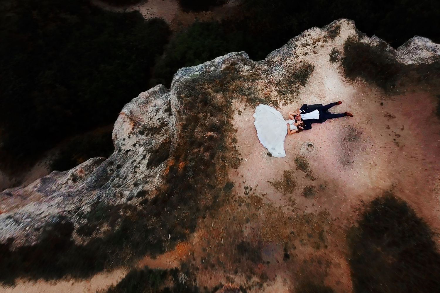 Silhouette of person leaping between rocky cliffs against dramatic sky.