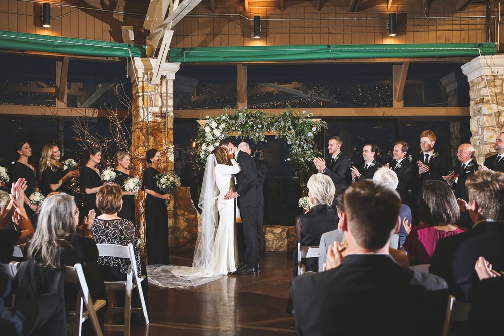 Wedding ceremony in rustic venue with guests seated and ceiling decorations.