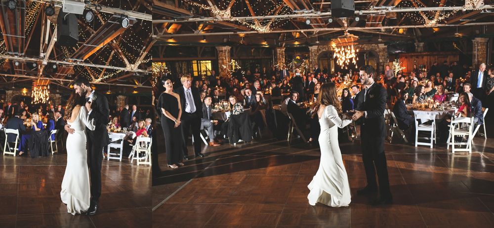 A couple shares their first dance at an elegant wedding reception with guests watching.