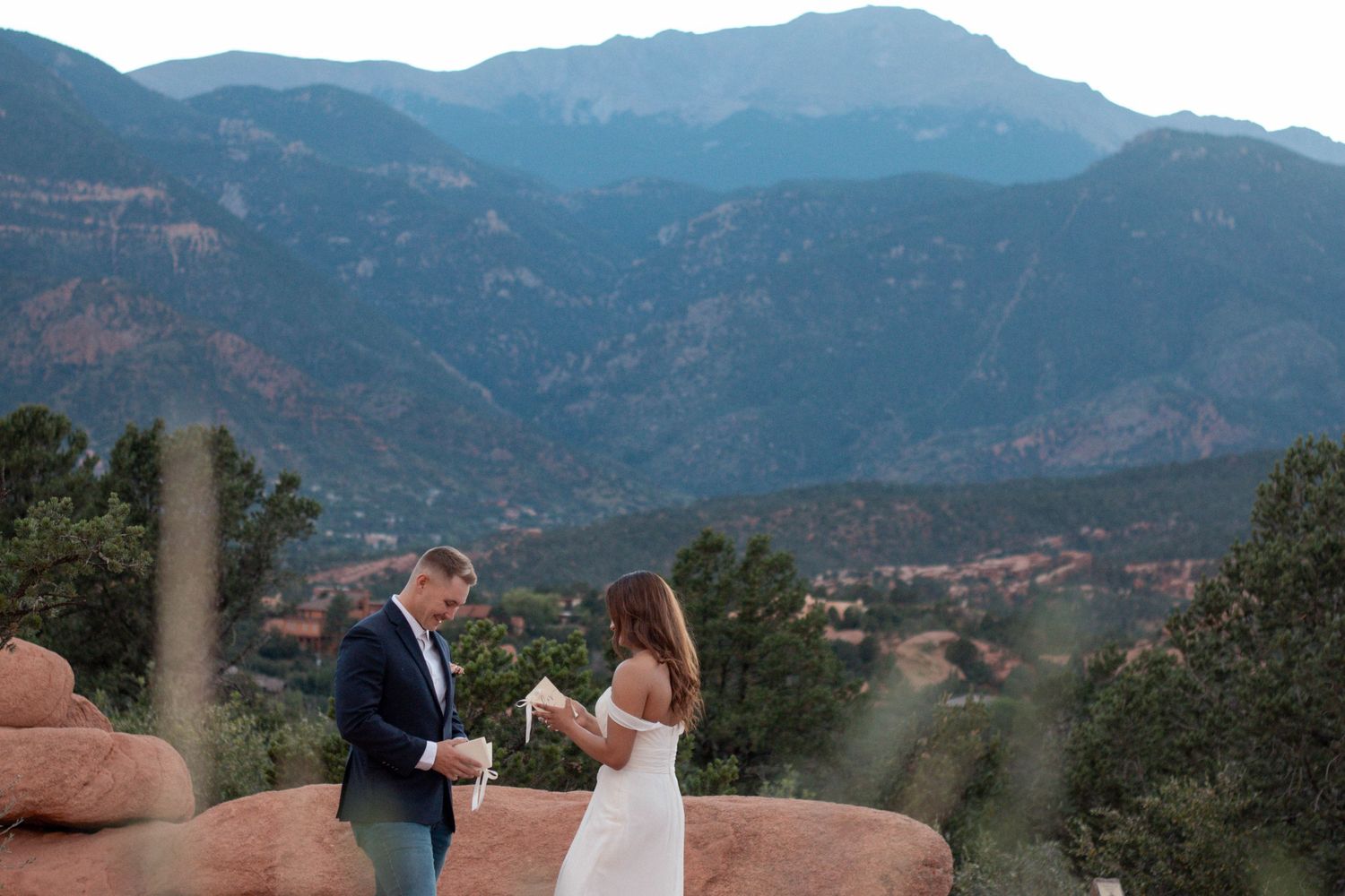 A romantic couple in wedding attire shares a moment at the Garden of the Gods with mountains in the background. Elopement, vows photographer