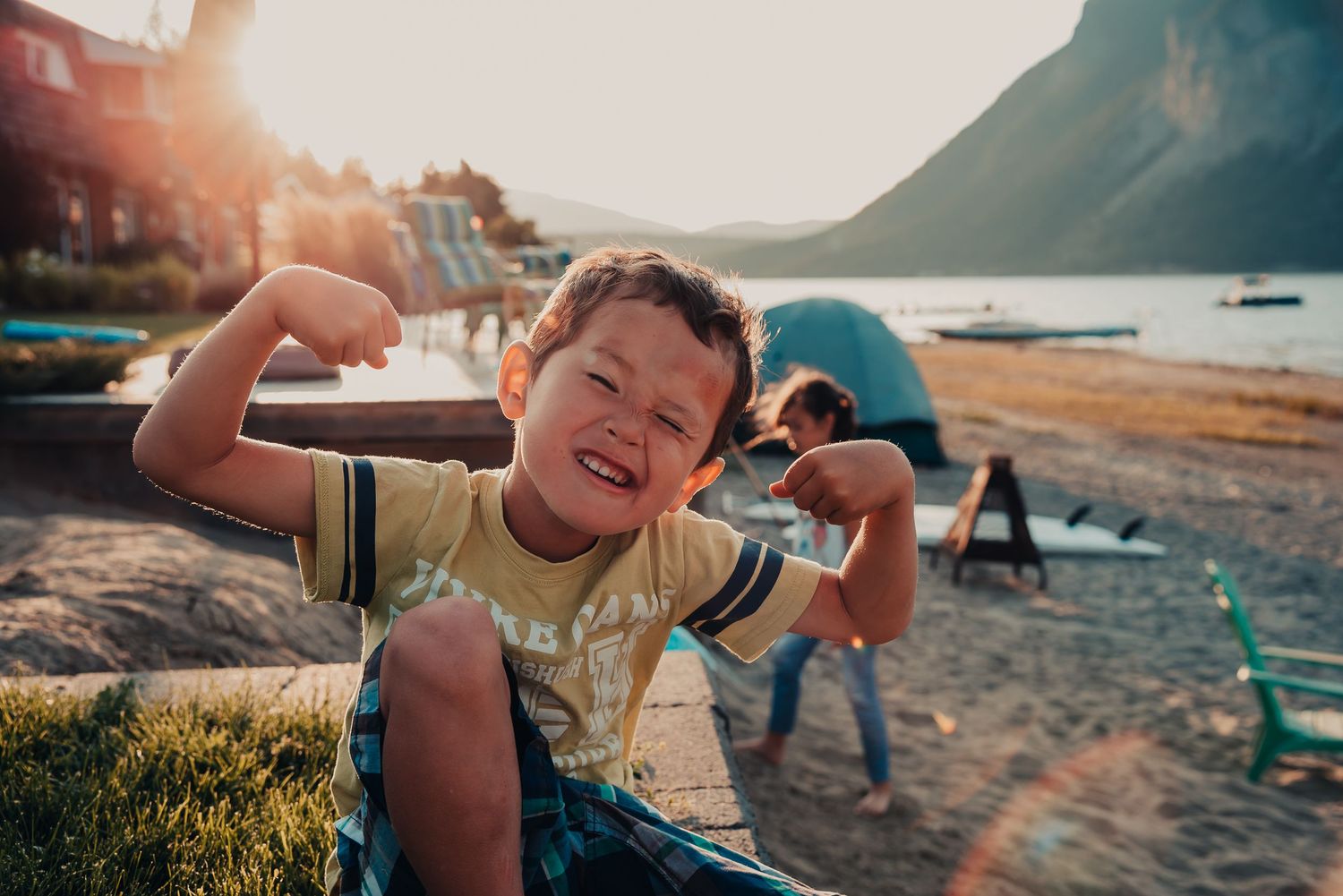 Child laughing joyfully during sunset at a scenic coastline.