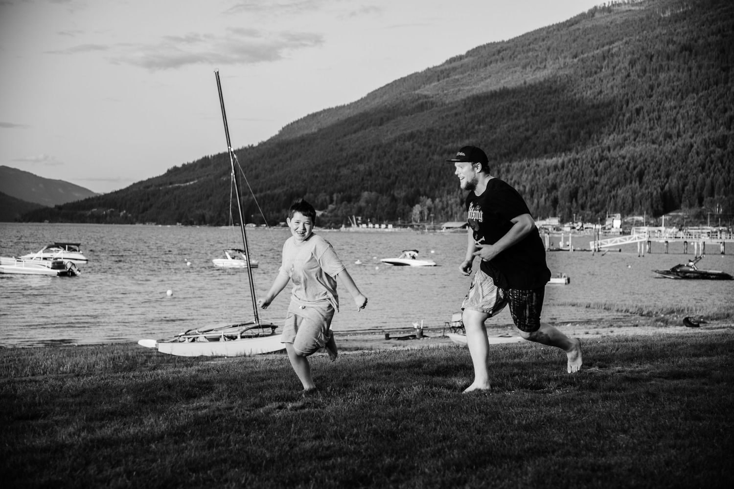Two people running and playing by a scenic lake in black and white.