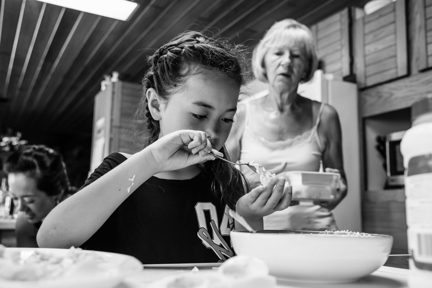 Family gathering around a table sharing a meal in black and white.