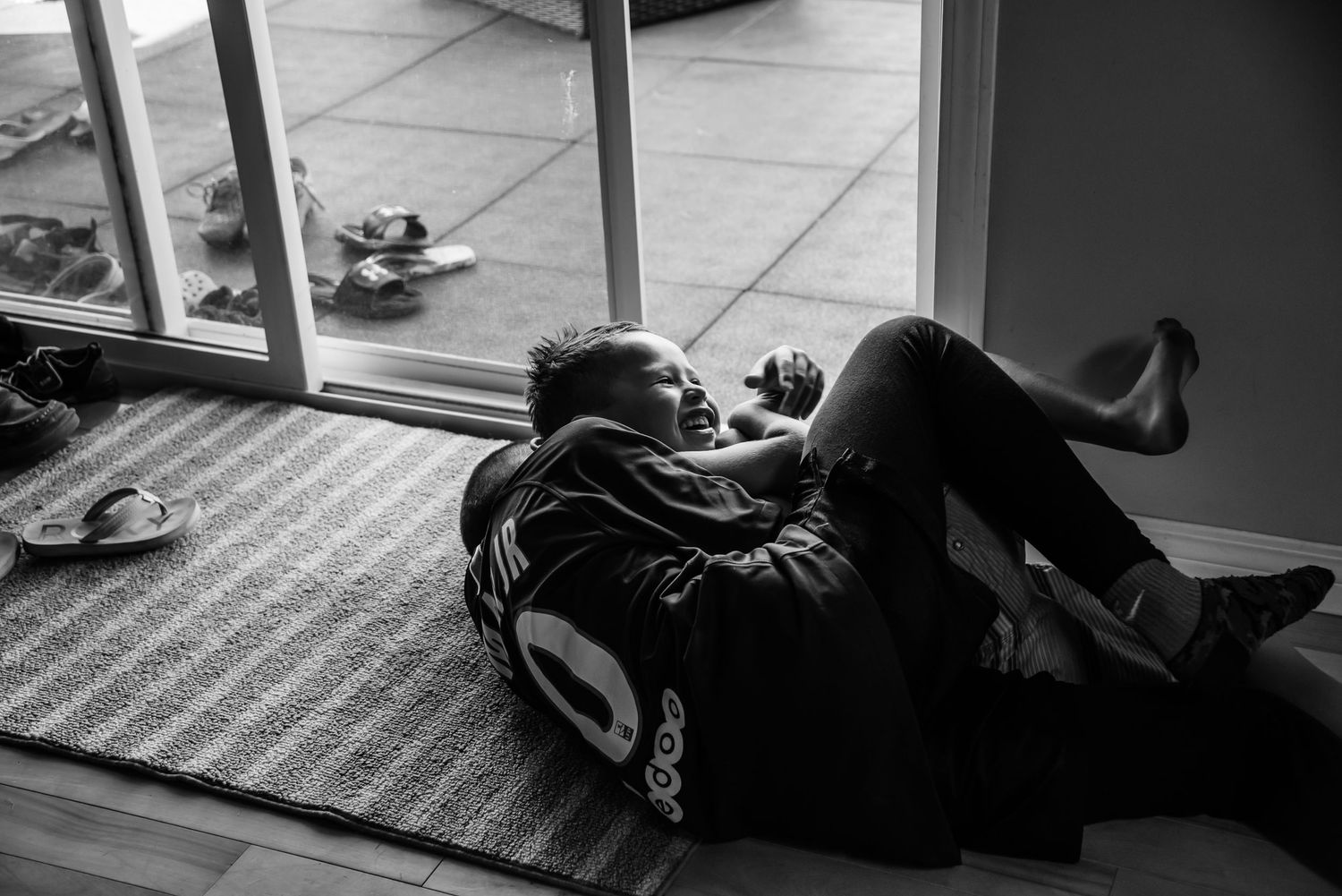 Person lying on carpet near glass doors in black and white photography.