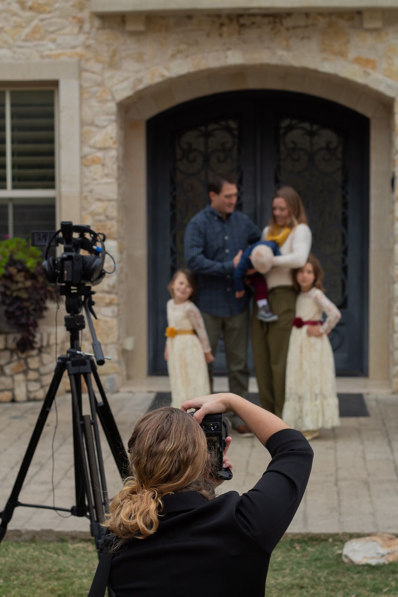 Photographer capturing a family portrait session at the entrance of a stone home.