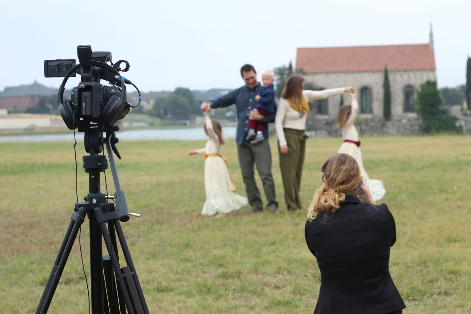Photographer and videographer capturing a family portrait session in an open field.