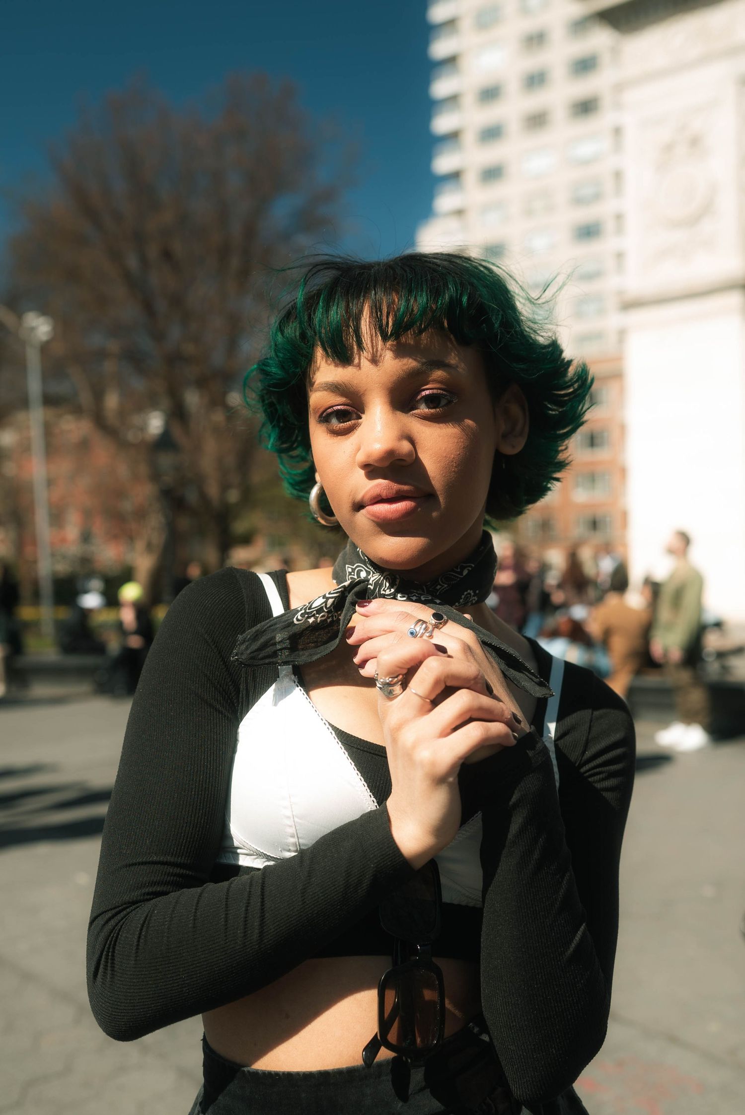 Person in black and white clothing posing playfully in an urban setting.
