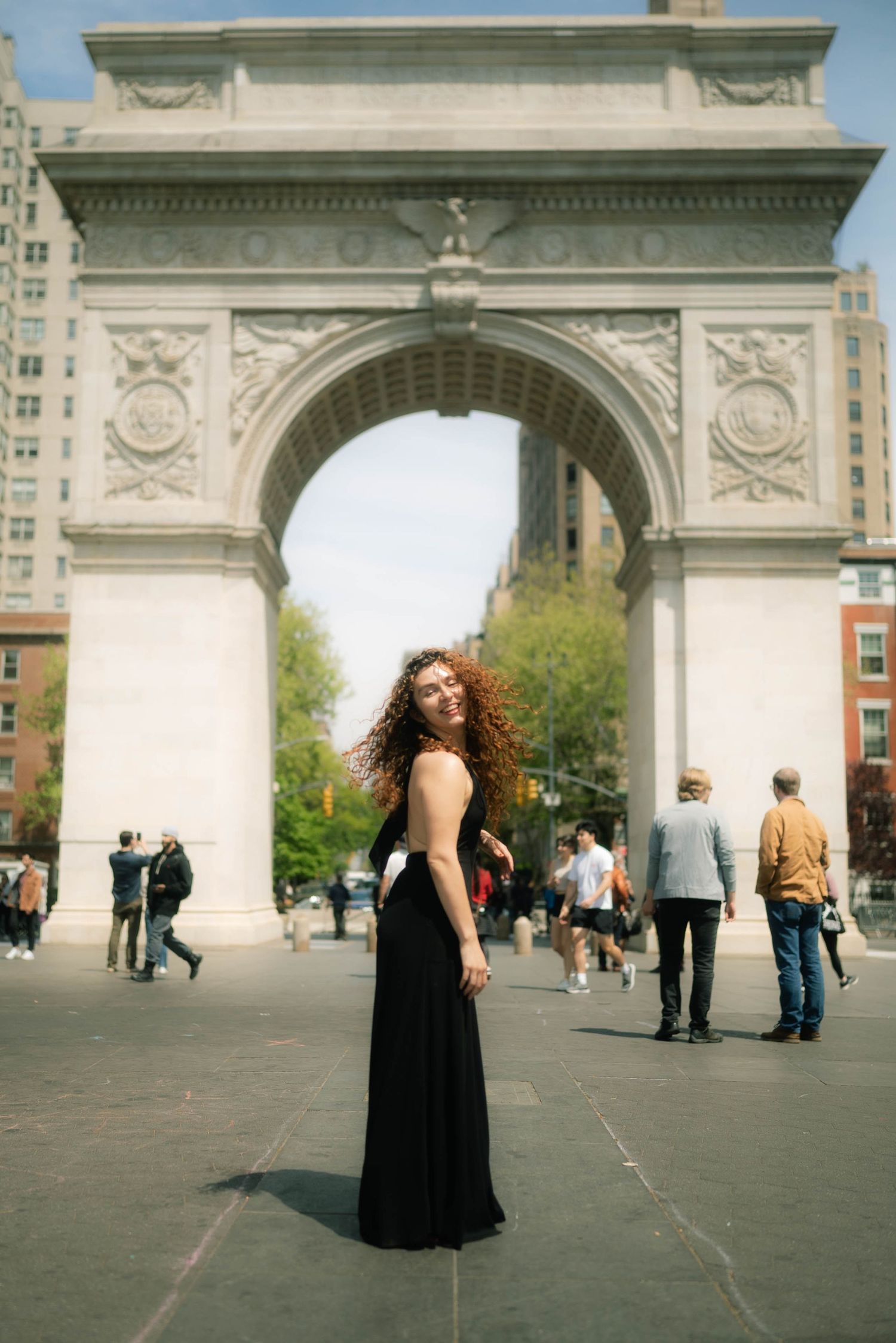 A series of dramatic poses in a black dress near Washington Square Arch.