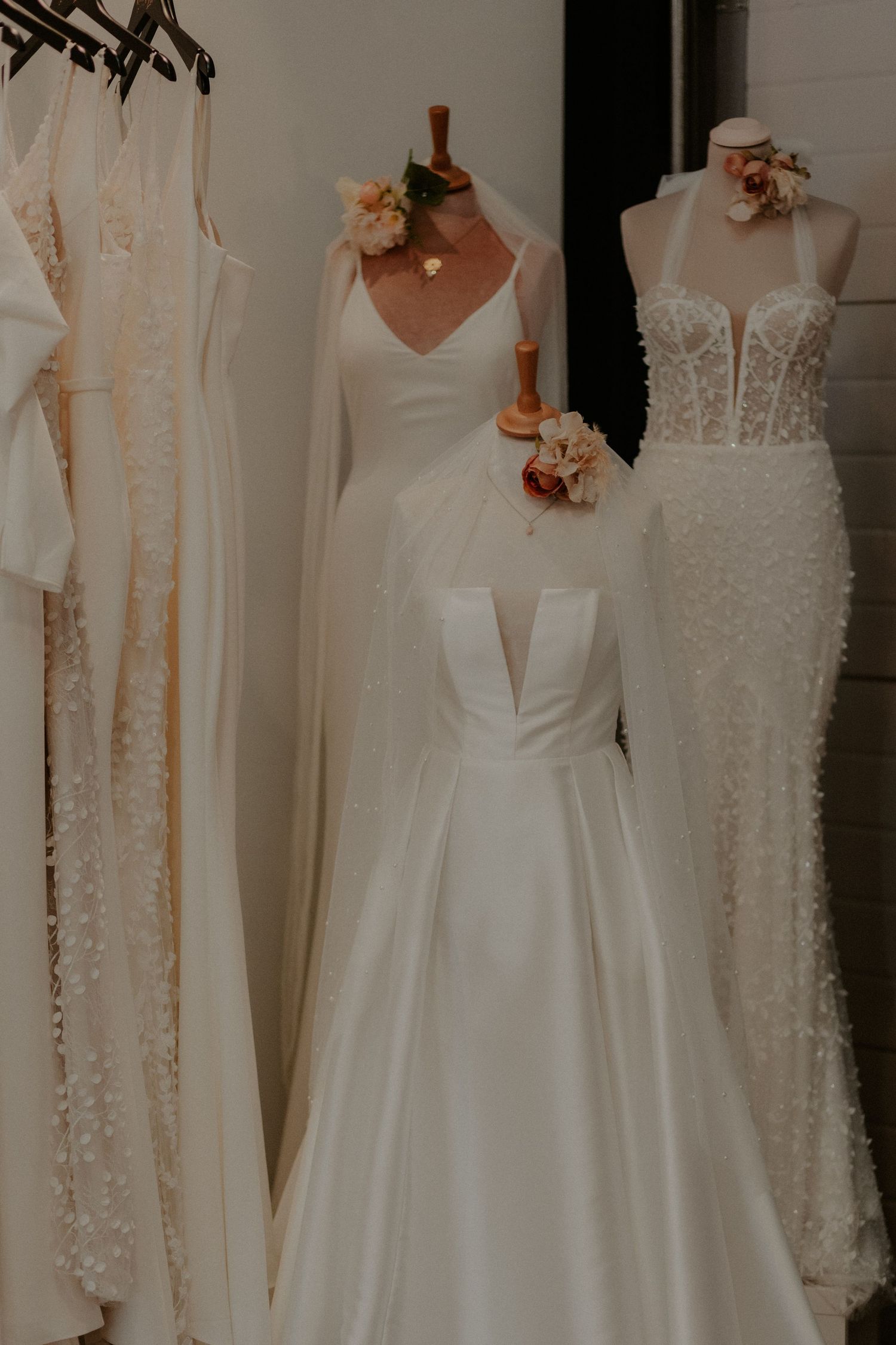 Wedding dress display featuring elegant white gowns with lace details and floral accents.