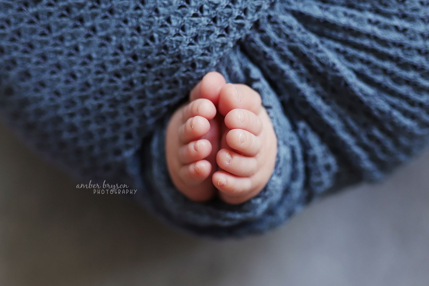 Close-up of tiny baby feet wrapped in blue knitted blanket.