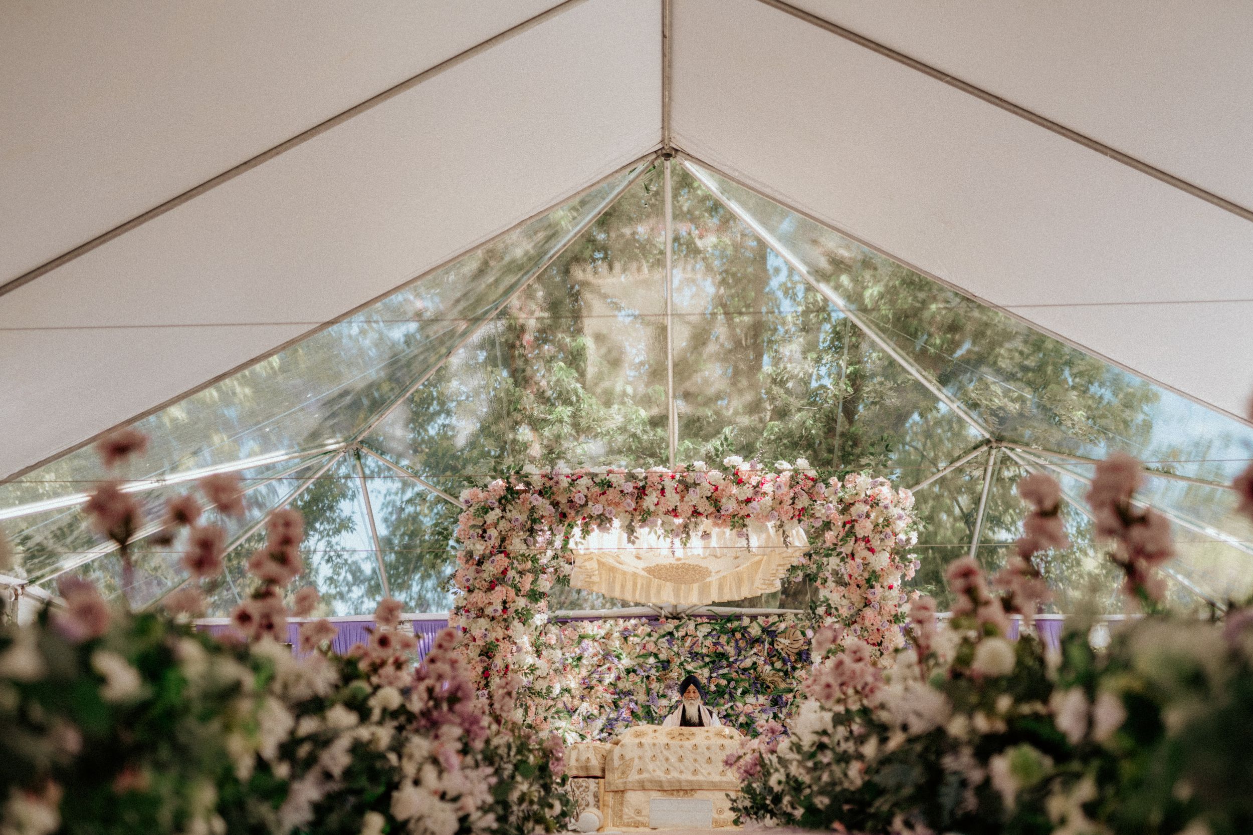 Elegant wedding tent interior decorated with floral arrangements and crystal chandeliers.