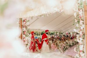 Dreamy wedding ceremony under a tent decorated with pink floral garlands and purple drapery.