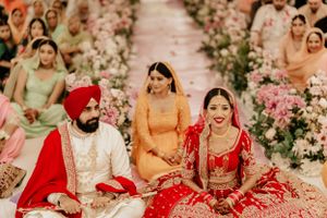 Traditional Sikh wedding ceremony with red and floral decor under decorated tent.