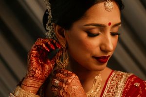 Detailed shot of traditional Indian bridal mehndi and jewelry against draped backdrop.