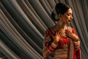 Side profile of traditional Indian bridal attire with detailed jewelry and red attire.