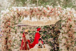 Wedding mandap adorned with pink and white floral archways during traditional ceremony.