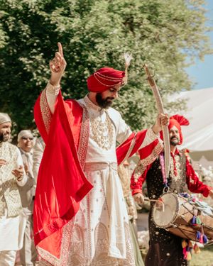 Traditional Indian wedding celebration with dancers in white and red attire performing outdoors.