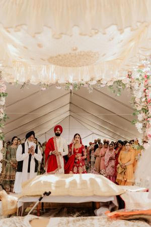 Wedding ceremony in an elegantly decorated tent with traditional Indian attire and floral decor.