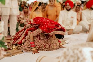 Ornate red and gold wedding attire displayed during traditional ceremony under white tent.