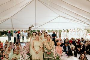 Guests gather under an elegant white tent for a traditional Sikh wedding ceremony with floral decorations.