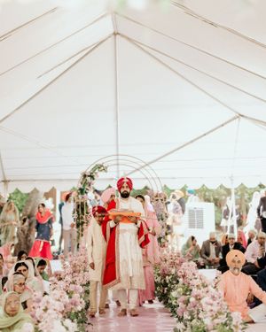 Wedding ceremony in white tent decorated with pink flowers and traditional decorative elements.