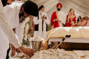 Traditional Sikh wedding ceremony preparations taking place under white tent.