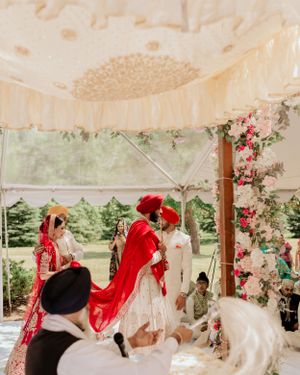 Traditional ceremony under tent decorated with pink and red floral arrangements.