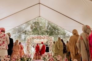 Wedding guests gathered inside white tent decorated with pink floral arrangements.