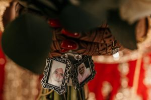 Small decorative photo frames with traditional Indian designs hanging on display at a wedding celebration.