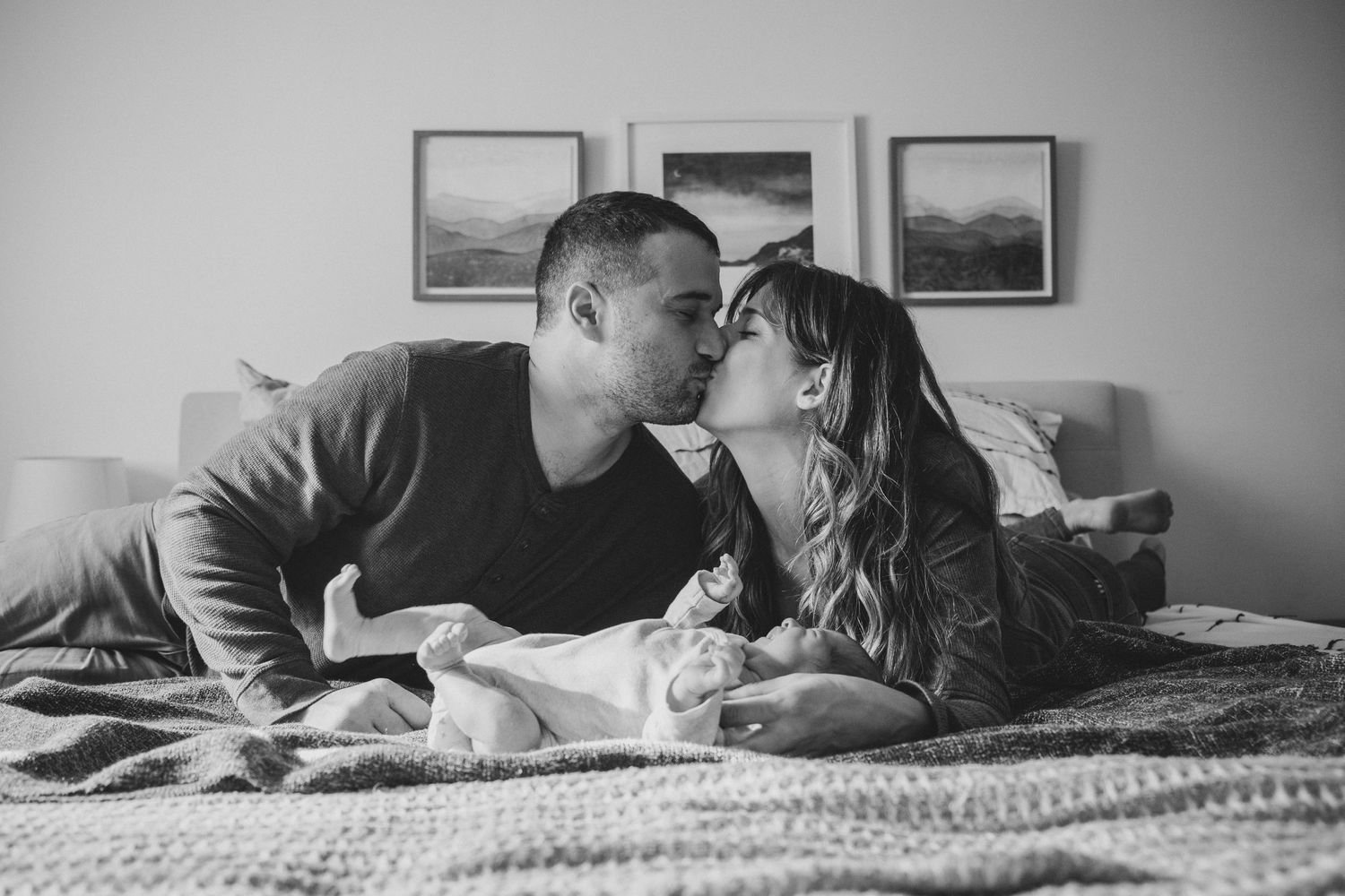 Intimate black and white photo of a couple sharing a tender moment on bed.