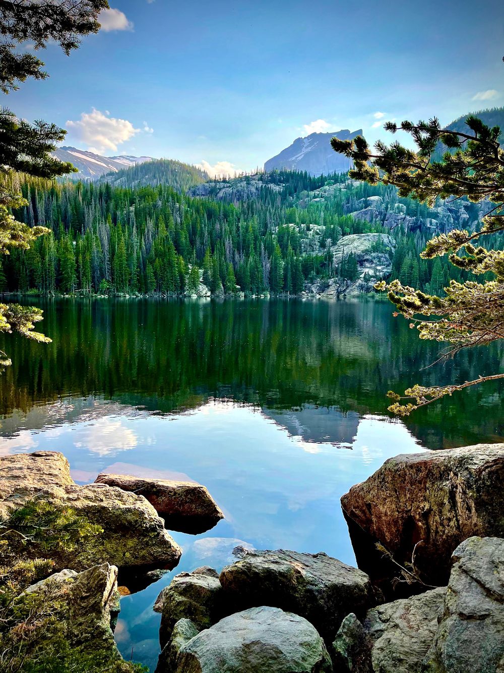 Stunning mountain lake reflection with evergreen forest and rocky shoreline in pristine wilderness.