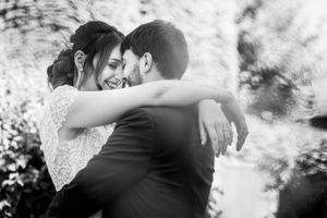 An intimate black and white moment between newlyweds sharing an embrace outdoors.