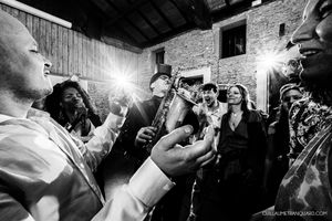 Black and white candid shots of wedding guests celebrating in a rustic brick-walled venue.