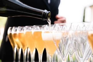 Champagne being poured into a row of elegant crystal flutes.