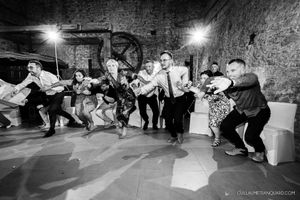 Wedding guests performing a choreographed dance routine in black and white photography.