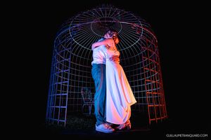 Artistic silhouette of dancing couples against illuminated blue and red geometric backdrop.