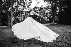 Dramatic black and white photos of flowing wedding dress in outdoor garden setting.