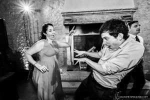 Black and white photo capturing energetic dance moves near a stone fireplace.