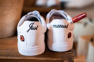 Close-up details of customized white wedding sneakers with decorative text and designs.